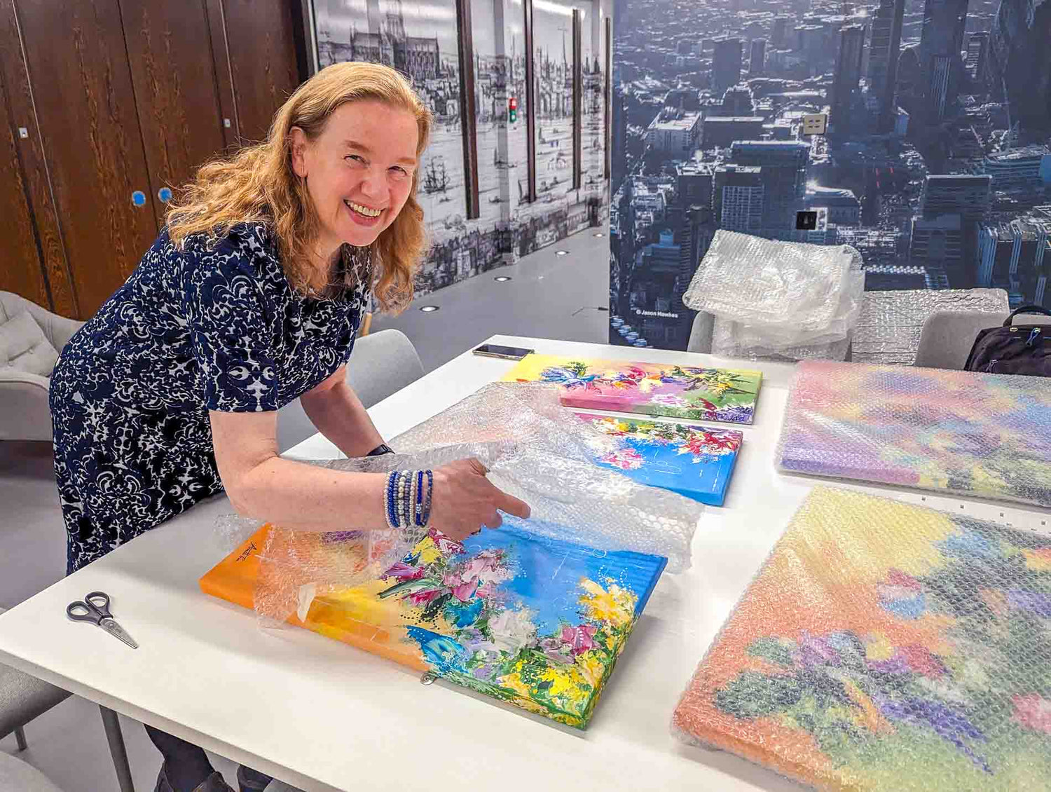Wendy Foster unwrapping a commissioned abstract painting at the Small Business Research and Enterprise Centre, London