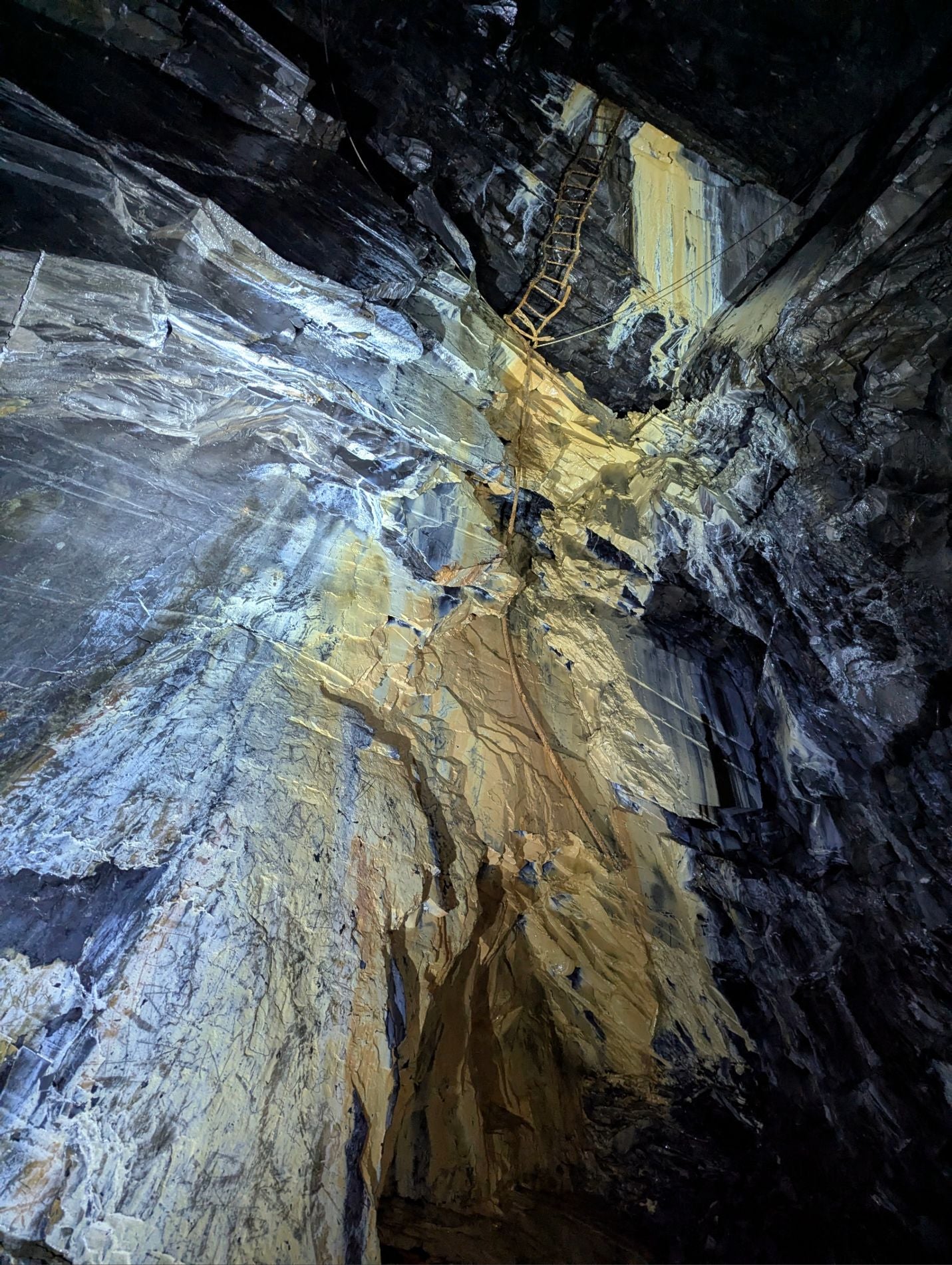 Inside a disused mine with rocky walls and a rickety ladder leading upwards
