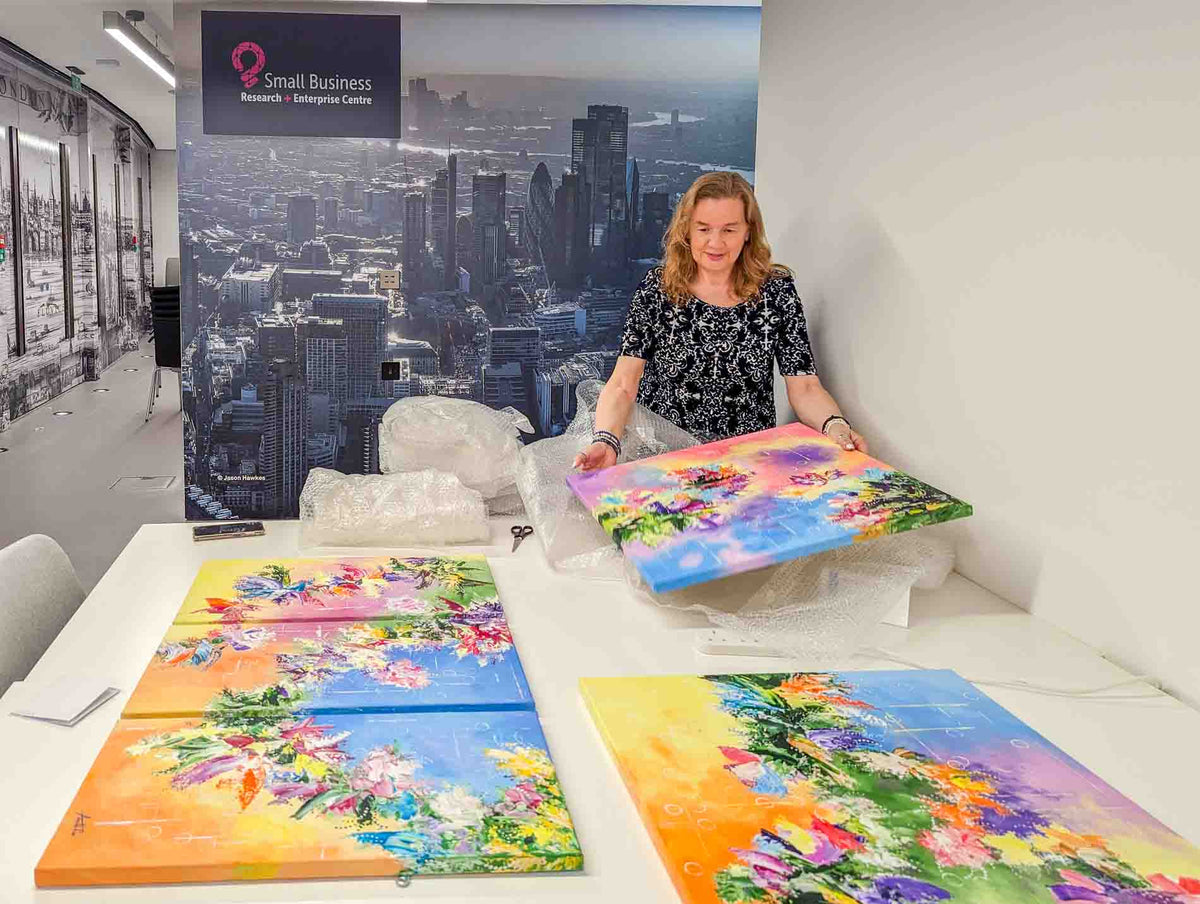 Wendy Foster unwrapping water-inspired abstract paintings, commissioned by the Small Business Research and Enterprise Centre, London.