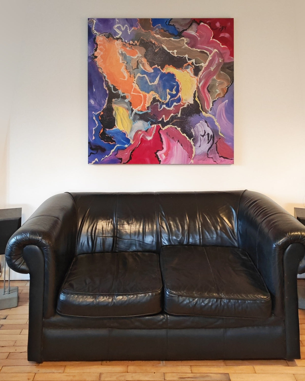 Hand-embellished 120 x 120 cm enlargement of an abstract painting by Annette Price, hanging above a black leather sofa in a collector's living room in Wales.